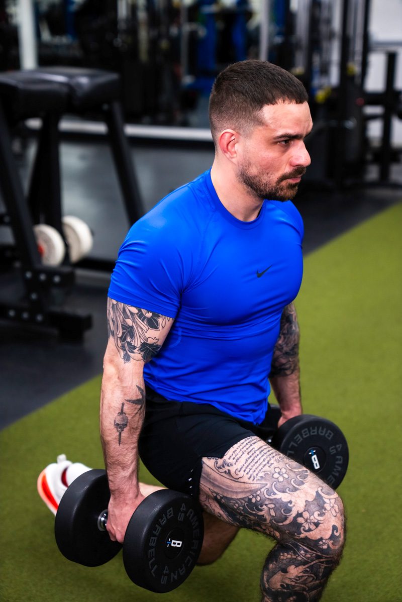 The coach performing a hanging leg raise, with a focused expression.